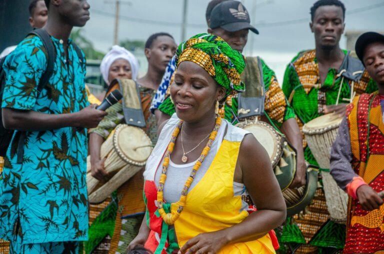 Colorful traditional West African drum performance with dancers and musicians outdoors.